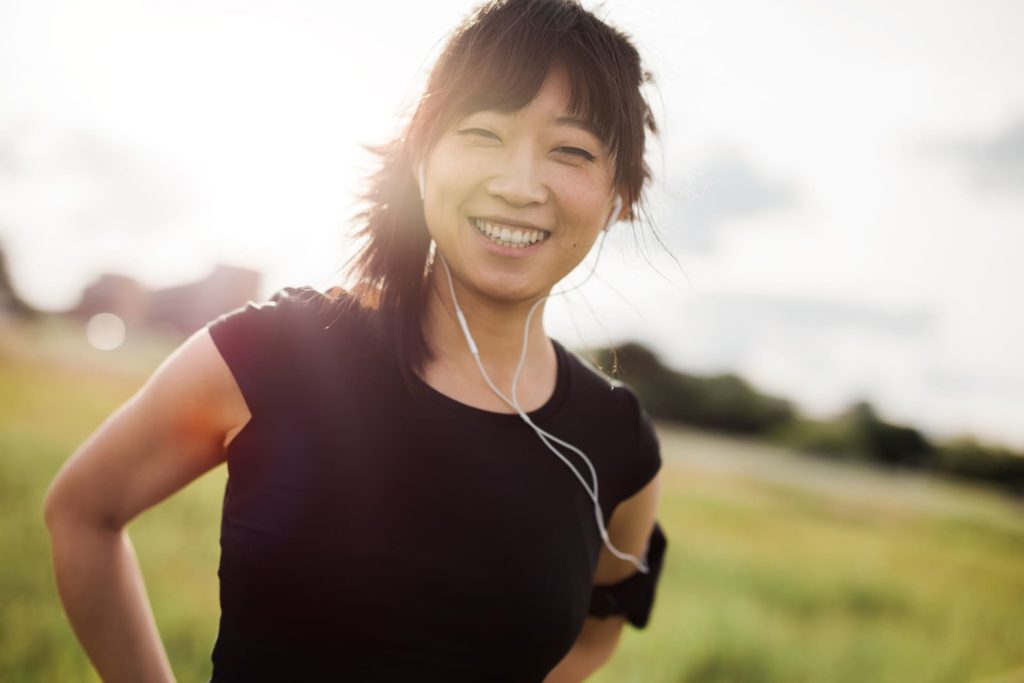 junge asiatische sportlerin lächelnd im grünen feld
